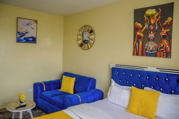 Et værelse med en seng, en blå sofa, et lille bord med en vase og et maleri på væggen.