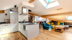 Un appartement moderne de style « loft », doté d’une cuisine et d’un espace de vie à aire ouverte, avec une verrière et des poutres en bois.