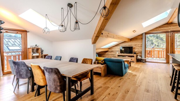 Un vaste espace de vie comprenant une table à manger en bois, plusieurs chaises, un canapé et un téléviseur.