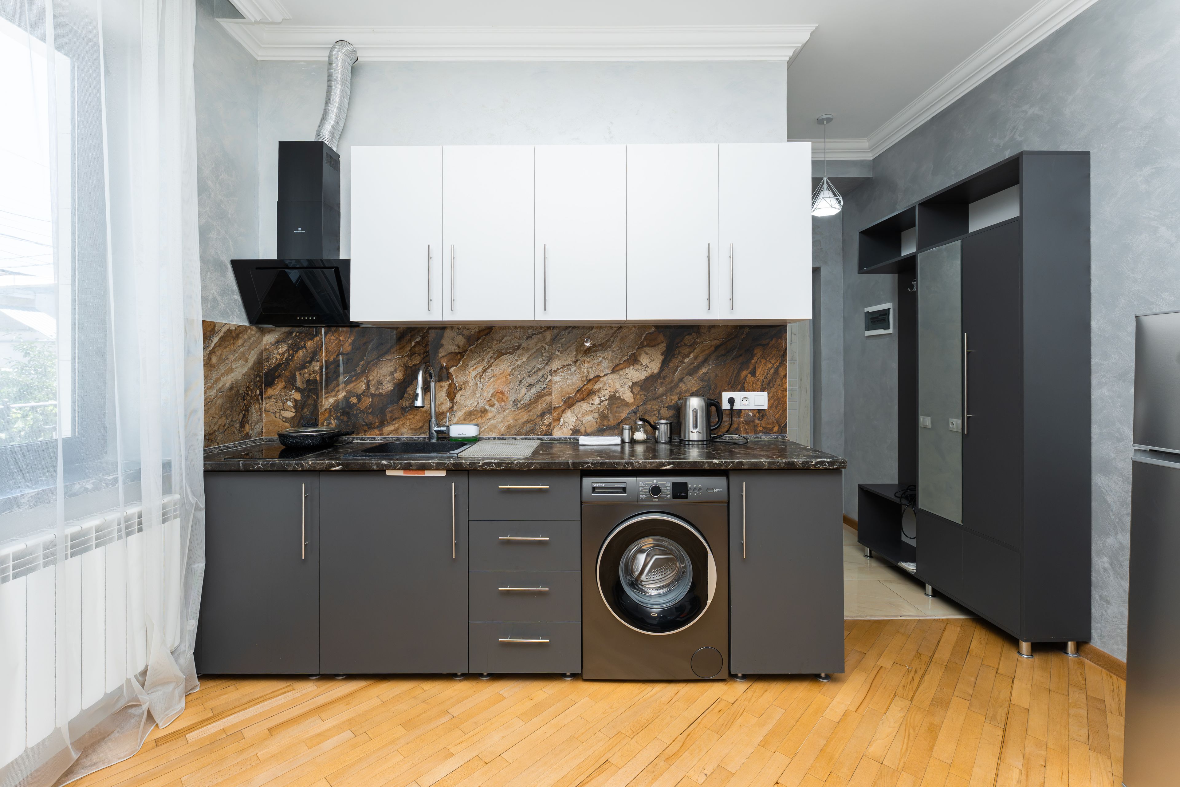 Eine moderne Küche mit integriertem Waschmaschine, einer großen Kochinsel und einem schwarzen Kühlschrank.