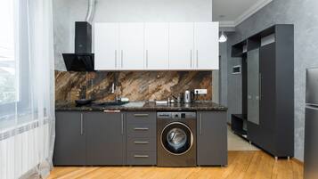 Eine moderne Küche mit integriertem Waschmaschine, einer großen Kochinsel und einem schwarzen Kühlschrank.