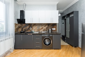Una cocina moderna con lavadora integrada, una isla grande y un refrigerador negro.