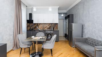 A modern kitchen with a marble backsplash, a dining area with a table and chairs, and a grey sofa.
