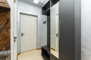 A hallway with a white door, a dark wall, and a mirror reflecting the door. - Zurabyan's Home (Yerevan)