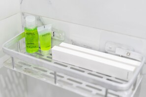 A bathroom shelf with two bottles of hotel shampoo and a white soap dispenser. - Zurabyan's Home (Yerevan)
