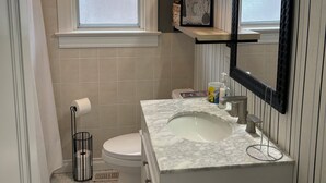 A bathroom with a toilet, sink, and window.