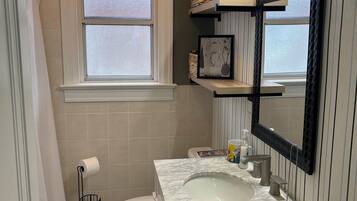 A bathroom with a toilet, sink, and window.
