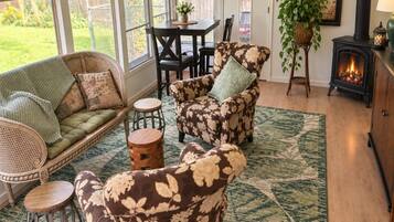 A cozy living room with a fireplace, comfortable seating, and a view of the outdoors.