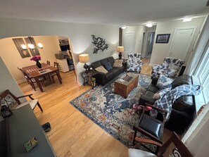 A living room with a sofa, armchairs, a coffee table, and a rug. There is a dining area with a table and chairs. - Peaceful, cozy, with room for 8,  Lilly's Pad is an ideal Brantford stay. (Brantford)