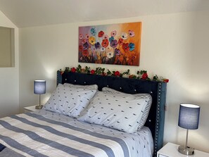 Ein Schlafzimmer mit einem Bett, zwei Nachttischlampen, einem Vorhang mit floralen Verzierungen und einem Bild über dem Bett.