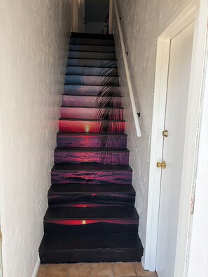 Eine Treppe mit Farbverlauf, die zu einer weißen Tür mit Messingklinke führt.