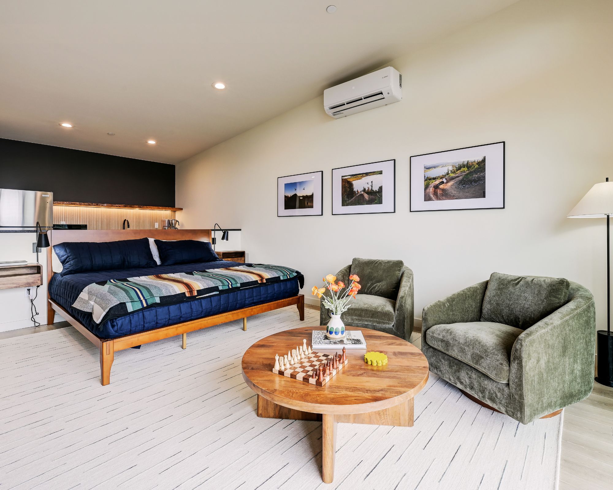 Ein modernes Schlafzimmer mit Bett, einer kleinen Küchenzeile und einer Wohnbereich mit Sofa und Couchtisch.