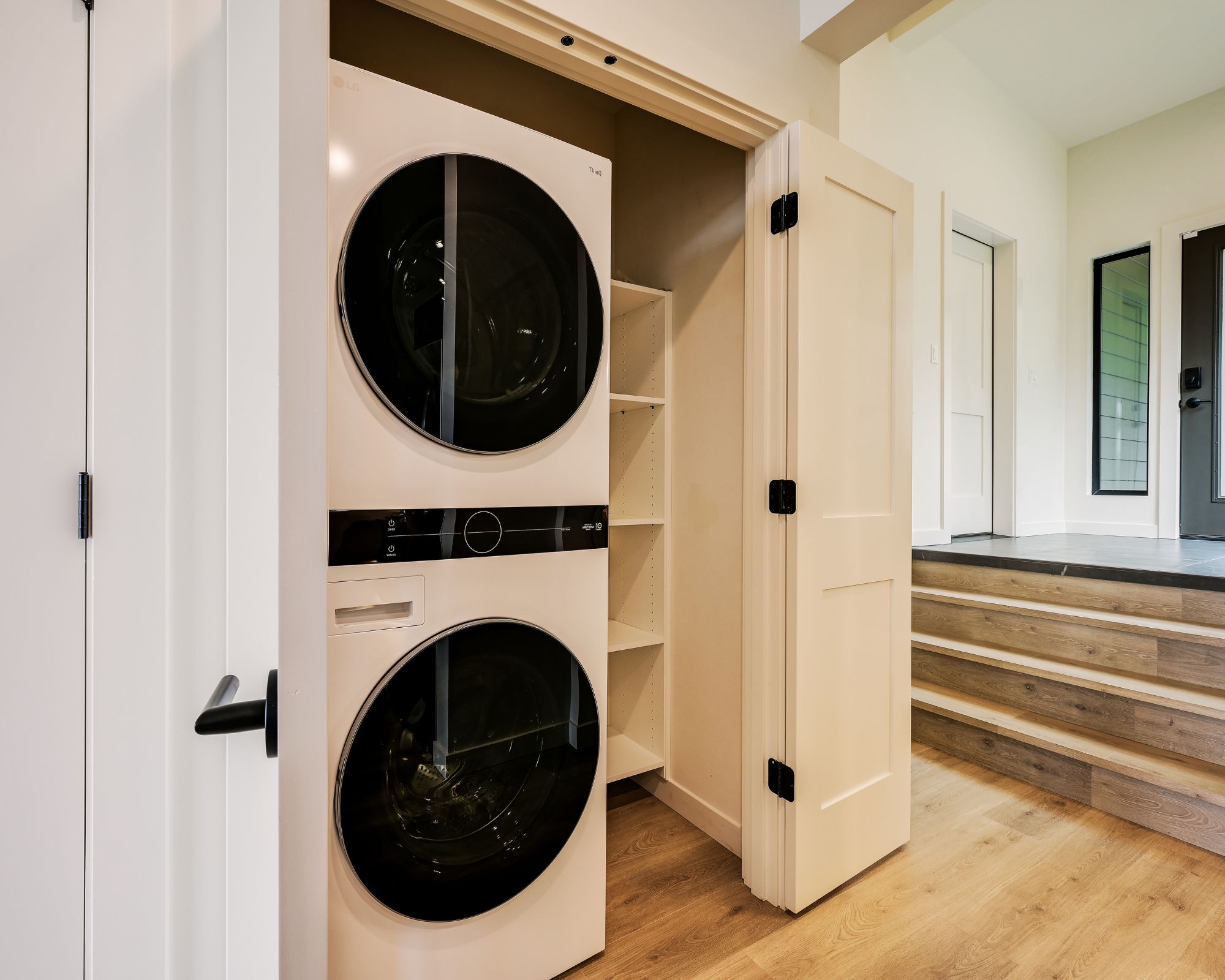 A laundry room with two front-loading washing machines, a control panel, and a white door.