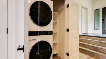 A laundry room with two front-loading washing machines, a control panel, and a white door.