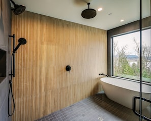 A modern bathroom with a wooden slat wall, a freestanding bathtub, and a shower area with a handheld showerhead.