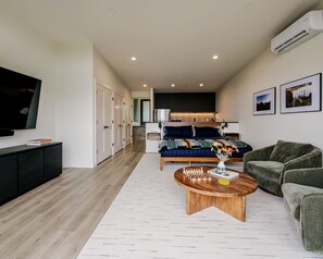 A modern living room with a flat-screen TV, a sofa, a coffee table, and a dining area in the background.