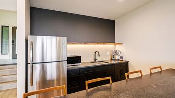 A modern kitchen with a stainless steel refrigerator, a microwave, and a coffee maker on the counter.