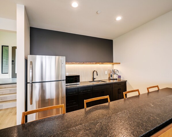 A modern kitchen with a stainless steel refrigerator, a microwave, and a coffee maker on the counter.