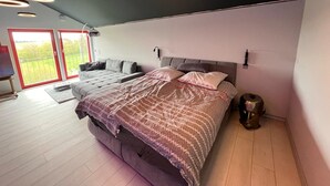 A modern bedroom with a large bed, a sofa, and a circular ceiling light fixture. - Vulkaneifel Artists' House (Mückeln)