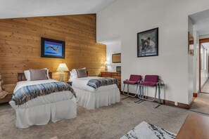 A bedroom with two beds, wooden paneling on the walls, a framed picture, and a chair. - Park City Getaway | Pool Access + Near Skiing (Park City)