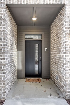 A modern building entrance with a dark door, a small window above the door, and the number 11 on the wall. - Spacious 4-Bedroom Townhome in Excellent Nashville Area • 10 Min to Broadway (Nashville)