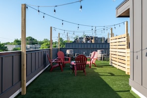 An outdoor patio with artificial grass, red chairs, a table, and string lights. - Spacious 4-Bedroom Townhome in Excellent Nashville Area • 10 Min to Broadway (Nashville)