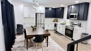 A modern kitchen with white cabinets, a stainless steel refrigerator, a microwave, and a stove. - Modern 4-bedroom house  with Country Vibes. (Belton)