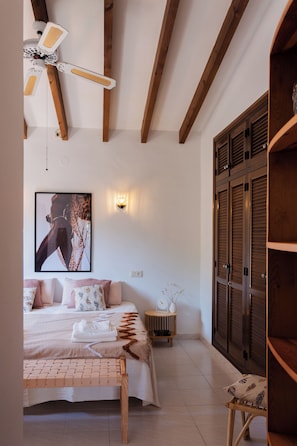 A bedroom with a bed, a bench, a wall-mounted light, a painting, and a wardrobe. - Beautiful villa on the Costa Blanca, with a pool, ocean view, garden, and close to the beach and Dénia. (Pego)