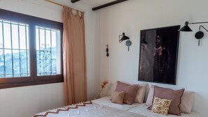 A bedroom with a large bed, a ceiling fan, a window with curtains, and a wall-mounted lamp. - Beautiful villa on the Costa Blanca, with a pool, ocean view, garden, and close to the beach and Dénia. (Pego)