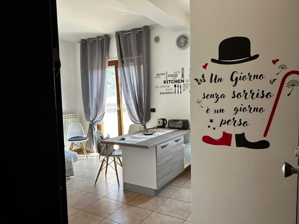 Una cocina moderna con una isla central, un comedor con sillas y una pared con una cita motivacional.