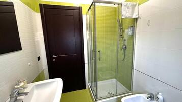 Un baño con ducha, lavamanos y bidé.