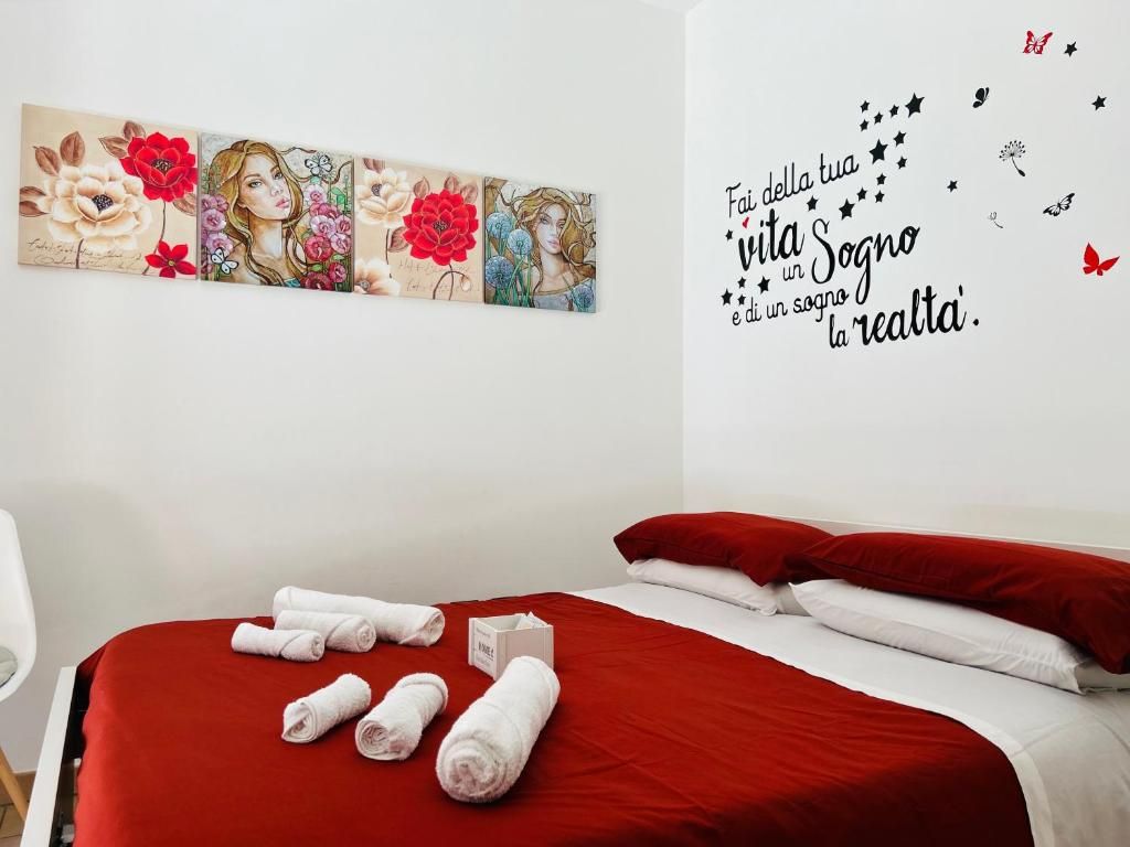 Una habitació d'hotel amb un llit, roig, una obra d'art a la paret i una cita motivacional.