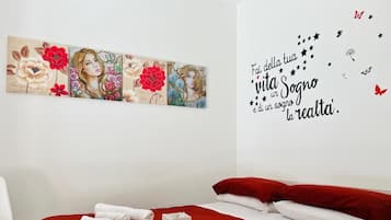 Una habitació d'hotel amb un llit, roig, una obra d'art a la paret i una cita motivacional.