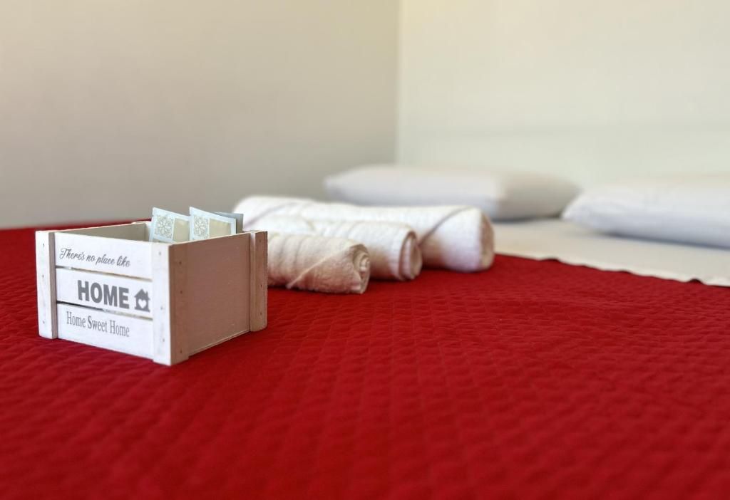 Ein Bett mit weißen Laken und einer rot gesteppten Tagesdecke.