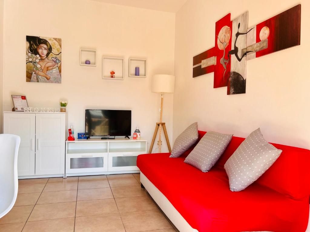 Ein Wohnzimmer mit einem roten Sofa, einem Fernseher und Kunstwerken an den Wänden.