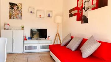 Ein Wohnzimmer mit einem roten Sofa, einem Fernseher und Kunstwerken an den Wänden.