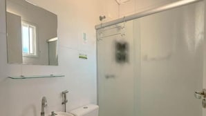 Un baño con lavamanos, inodoro y cabina de ducha de vidrio.