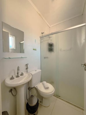 A bathroom with a sink, toilet, and glass shower enclosure. - Hotel Emburi (Piratininga)