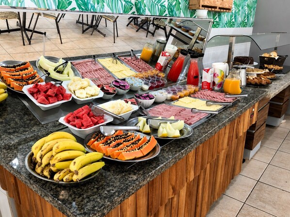 A buffet with various fruits, vegetables, and beverages.