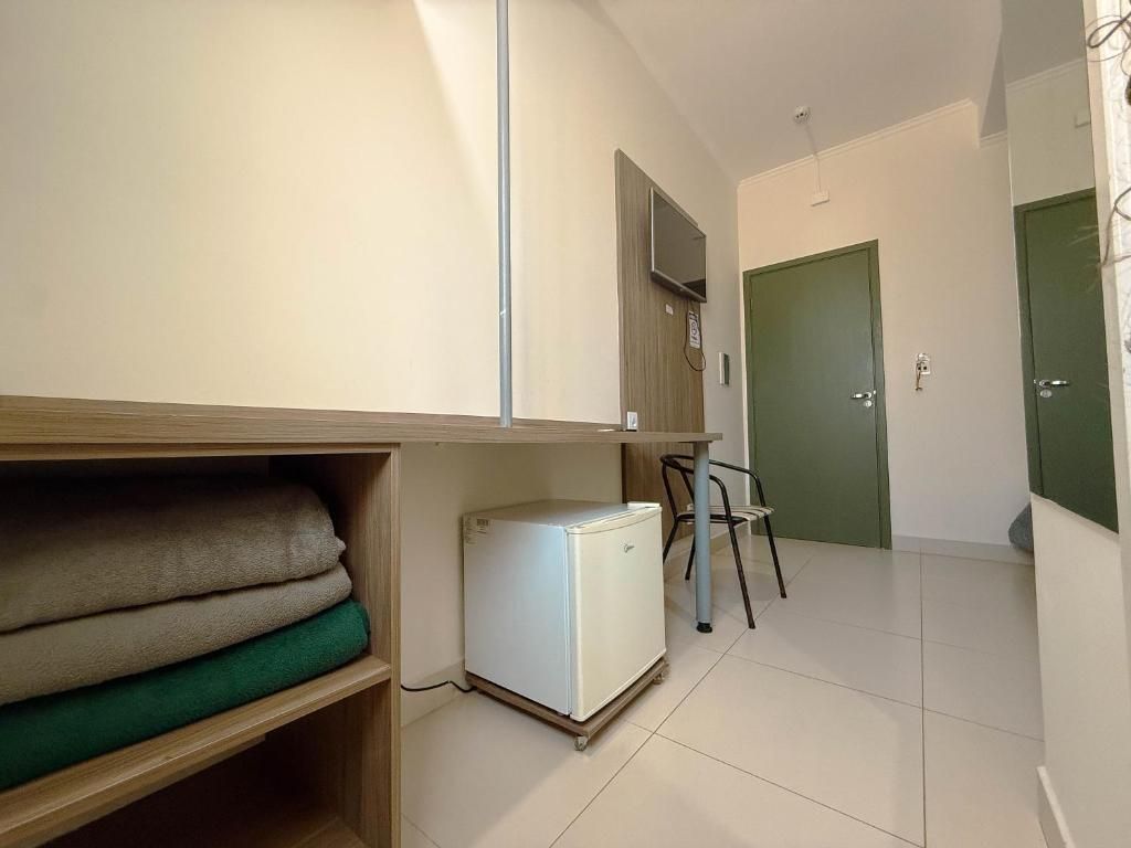 A small room with a bed, a desk, a chair, and a television mounted on the wall.