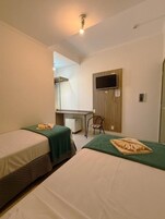 Habitación de hotel con dos camas, un escritorio, una silla y un televisor.
