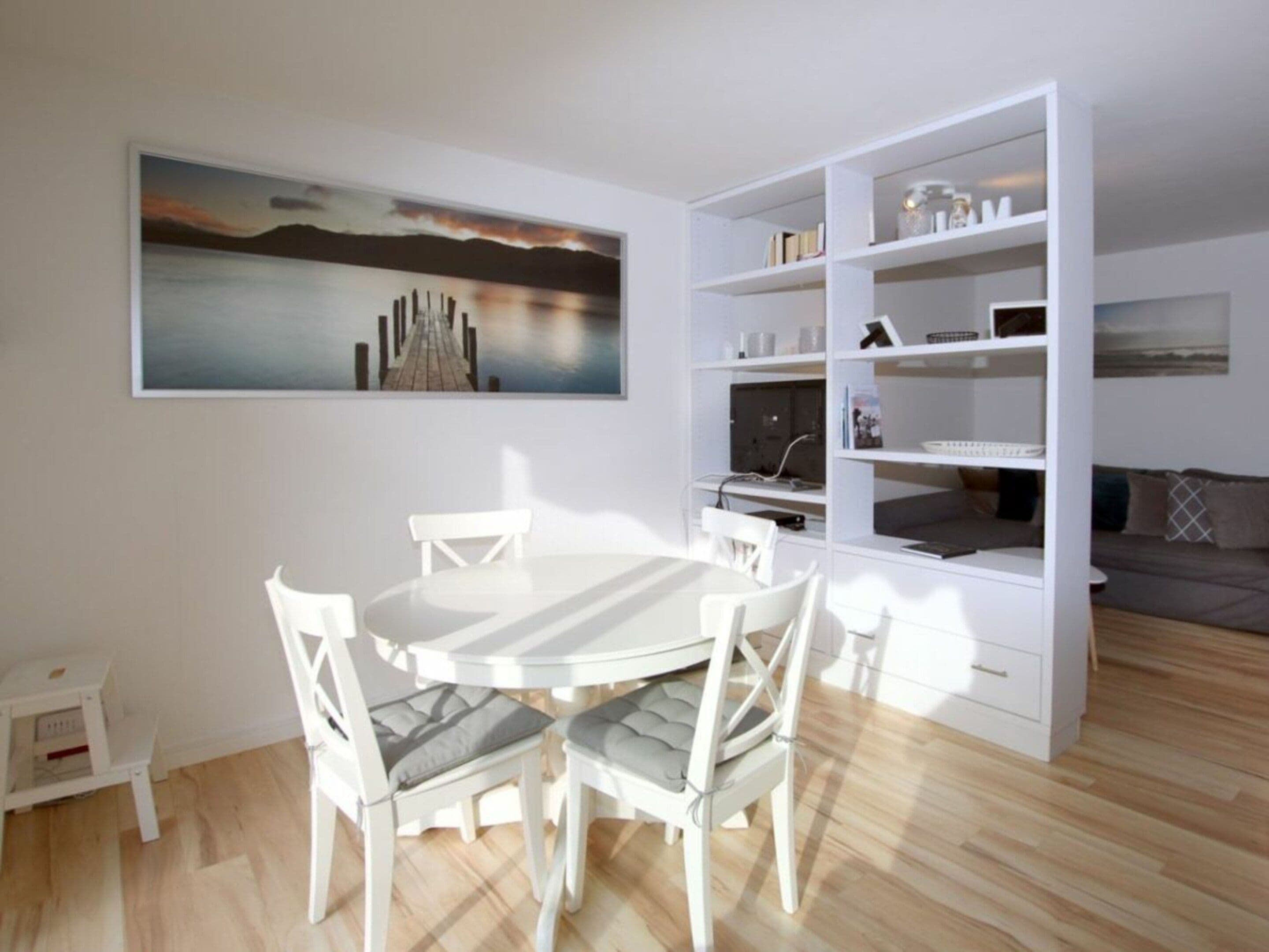 A modern living room with a dining area, a bookshelf, and a painting on the wall.