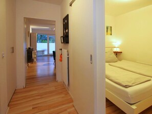 Ein Hotelzimmer mit Bett, Nachttischlampe und Blick durch eine offene Tür auf einen Balkon.