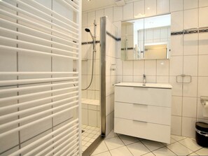 Ein modernes Badezimmer mit Dusche, Waschtisch und Spiegel sowie Toilette.