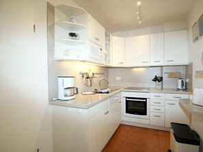 A compact kitchen with white cabinets, a coffee maker, a kettle, and a toaster. - Fasanenweg 2b, Holiday Apartment 2 (Wyk auf Foehr)