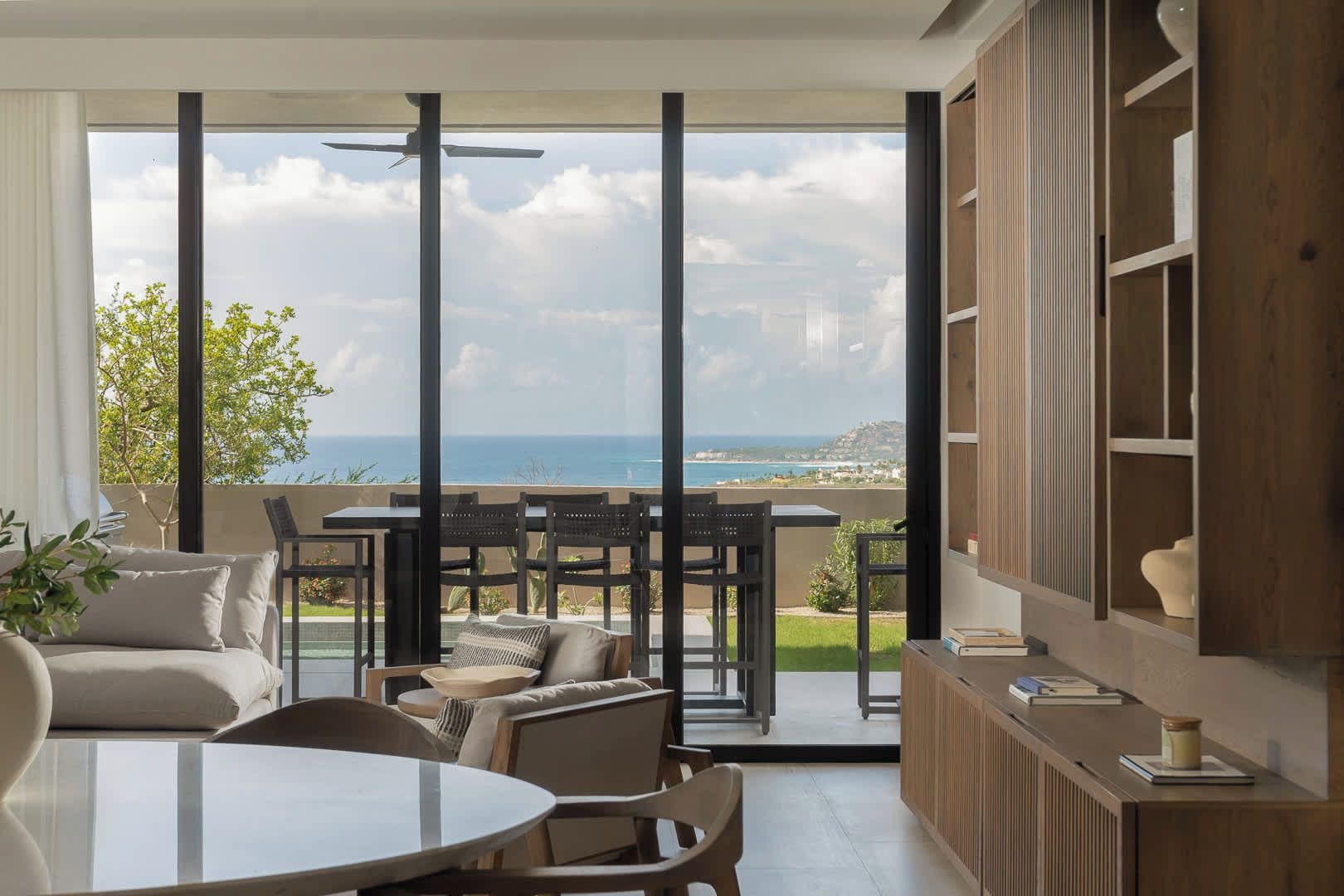 Un salon moderne doté d’une grande porte vitrée donnant sur un balcon avec vue sur la mer.