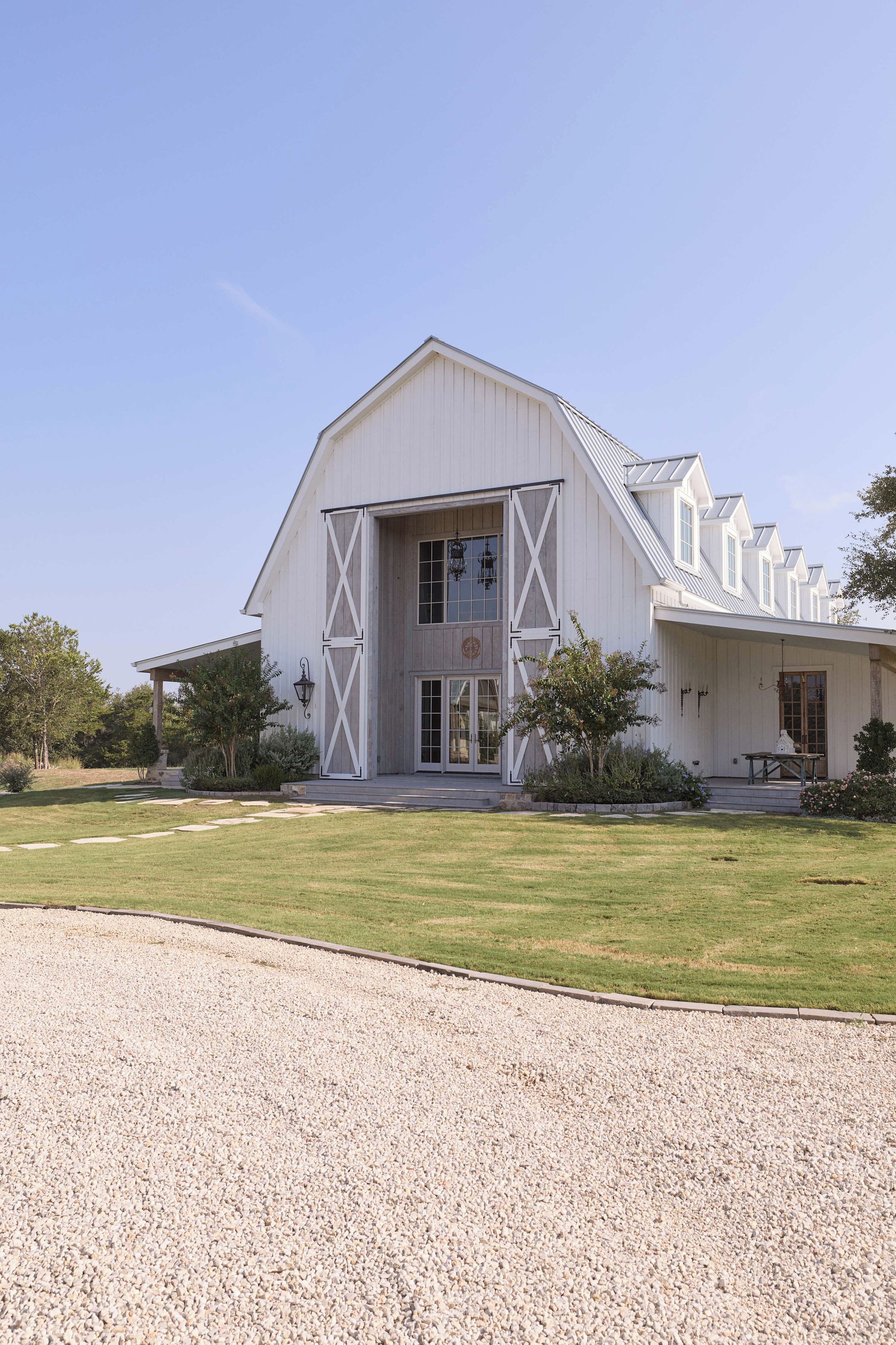 A large white barn-style building with a prominent entrance and a gravel driveway.