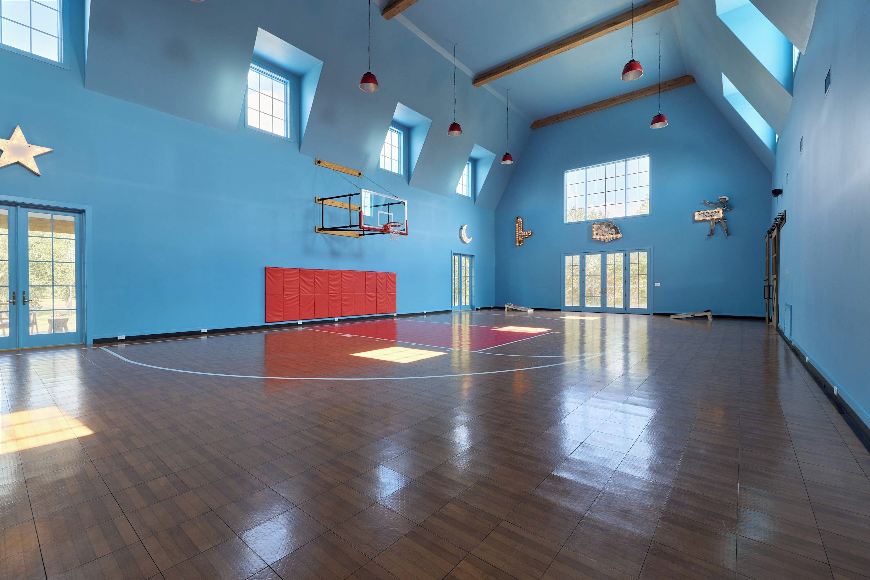 A spacious indoor area with a basketball court, wooden beams, and a basketball hoop.