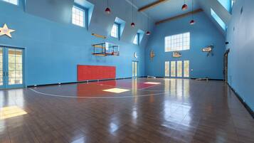 A spacious indoor area with a basketball court, wooden beams, and a basketball hoop.