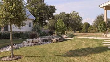 A residential property with a well-maintained lawn, a stone pathway, and a variety of trees.